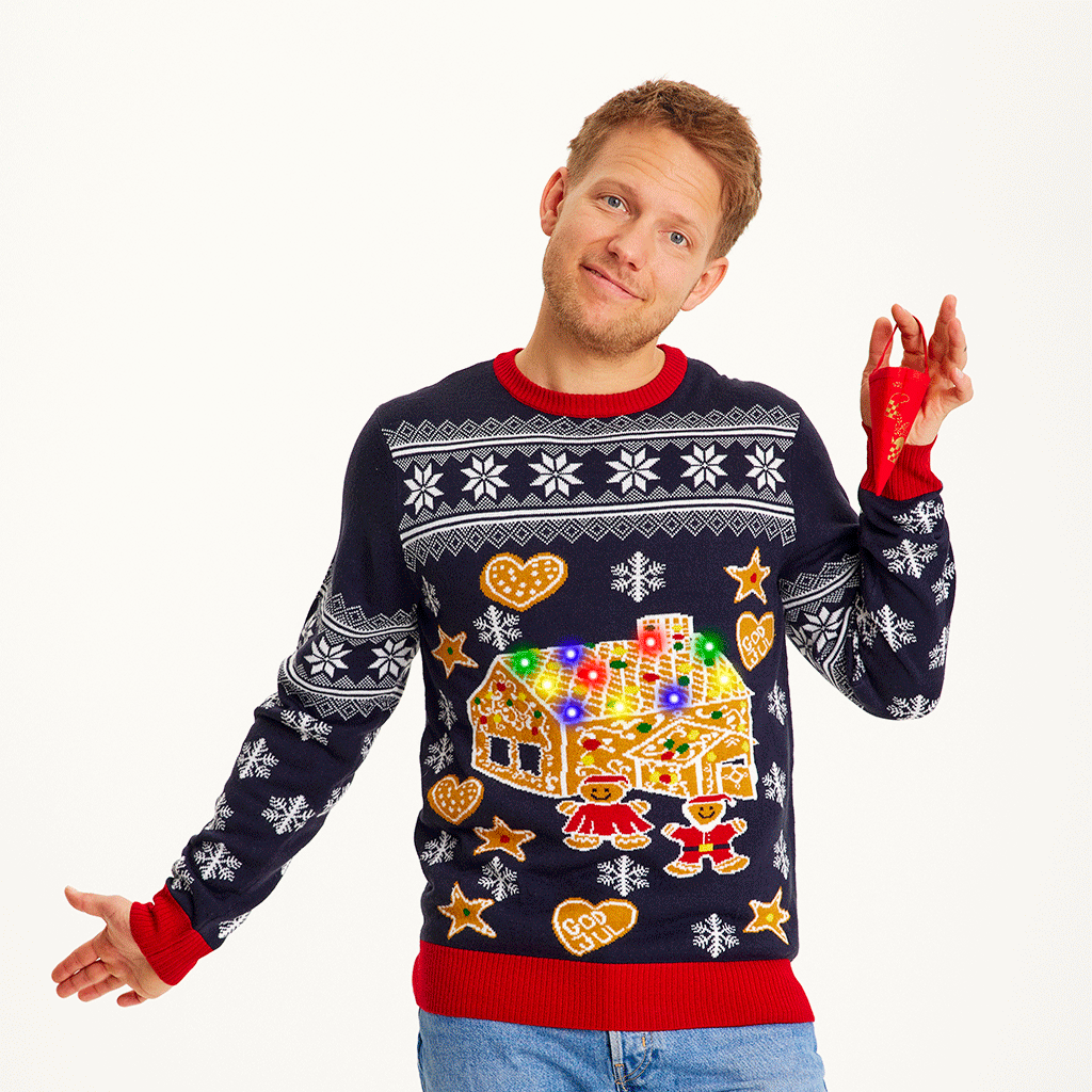 En mand iført en blå julesweater med et kagehus på.